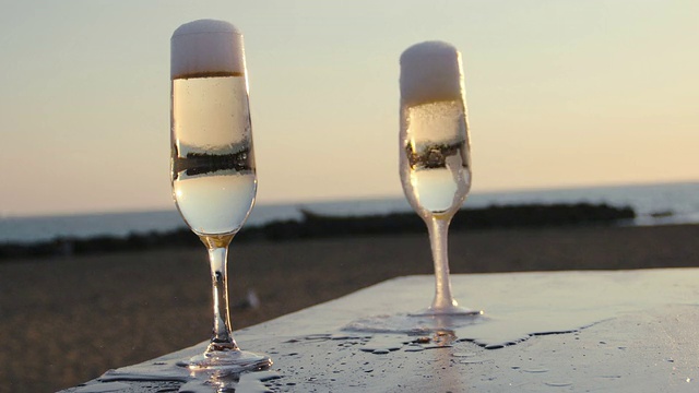 在海滩边往玻璃杯里倒白葡萄酒:夏天，日落，大海视频素材