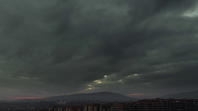 黑暗的暴风雨的云和日落在远处的城市与意大利的山的时间流逝视频素材