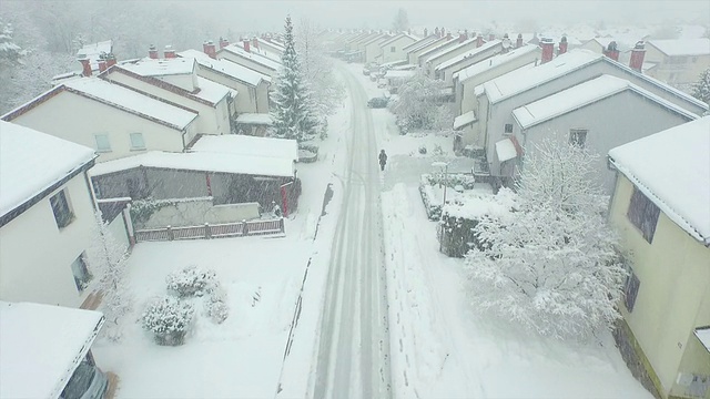 天线:一个孤独的人在暴风雪中穿过郊区的城镇视频素材