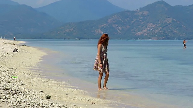 女孩穿着夏装走在美丽的海滩上视频素材