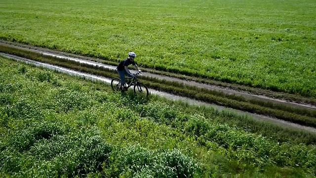 在乡村公路上骑自行车的人。鸟瞰图视频素材