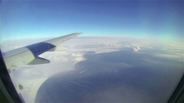 从飞行的飞机上可以看到蓝天、海洋和雪山。视频素材