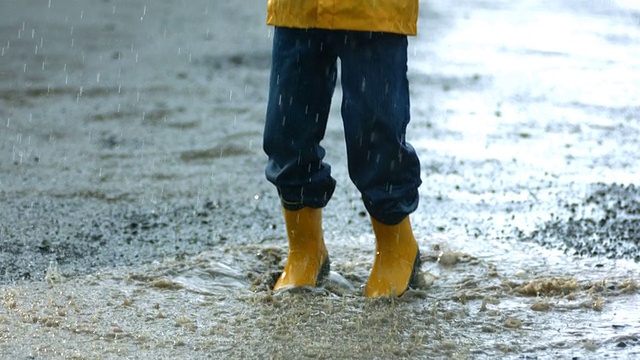 小男孩在雨中玩耍，慢镜头视频素材