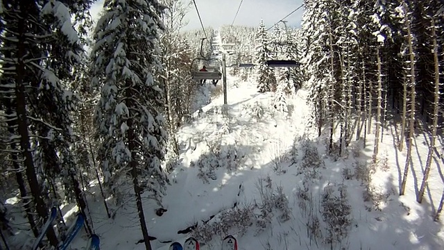 滑雪者站在滑雪缆车上。四周群山环抱，白雪皑皑。滑雪缆车上的景色视频素材