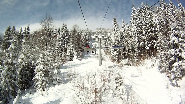 滑雪者站在滑雪缆车上。四周群山环抱，白雪皑皑。滑雪缆车上的景色视频素材