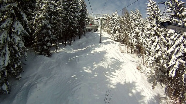 滑雪者站在滑雪缆车上。四周群山环抱，白雪皑皑。滑雪缆车上的景色视频素材