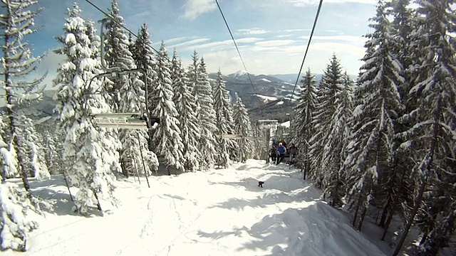 滑雪者站在滑雪缆车上。四周群山环抱，白雪皑皑。滑雪缆车上的景色视频素材