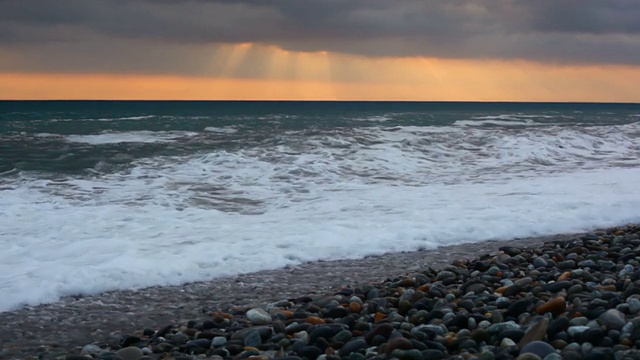 夕阳下卵石海岸上的海浪视频素材