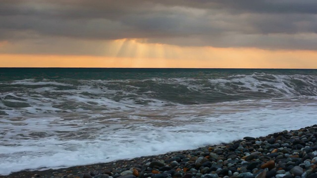 夕阳下卵石滩上的海浪视频素材