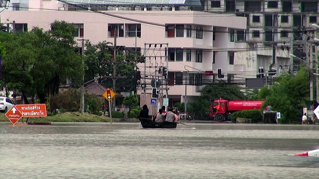 在被水淹没的街道上，人们坐在木筏上视频下载