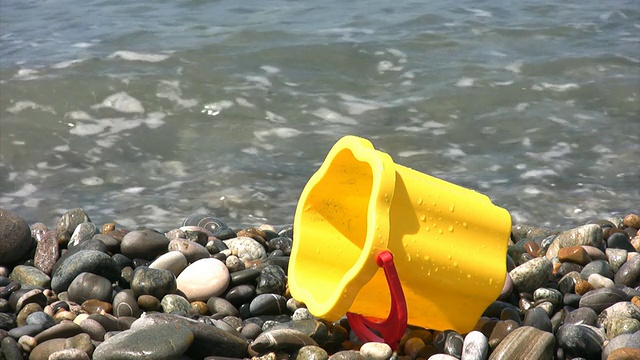 孩子们在岩石海滩上桶，海浪在背景视频素材