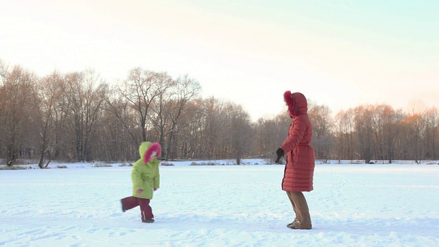 小女儿在冬天的雪地里跑向妈妈视频素材