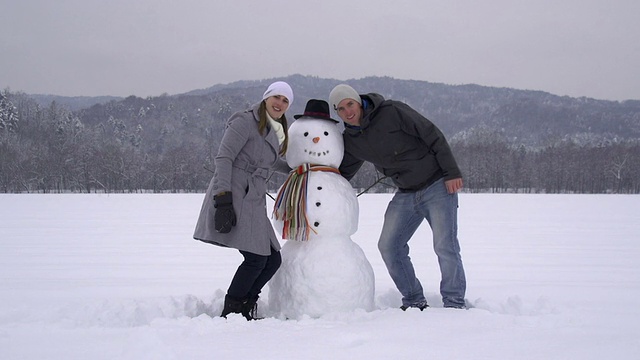 年轻夫妇在堆雪人视频素材