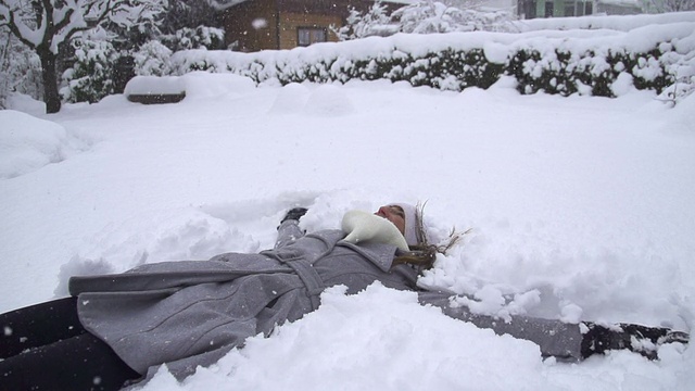 慢镜头:年轻女子在堆雪天使视频素材