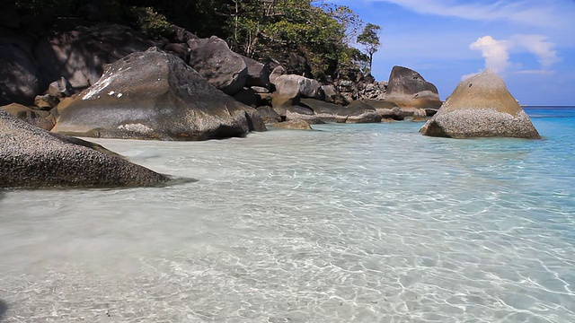 蓝色的海浪拍打着白色的沙滩和岩石。视频下载