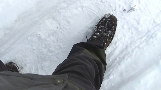 脚穿靴子，踏在雪地上。视频素材