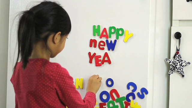 亚洲小女孩在冰箱上拼写新年快乐视频素材