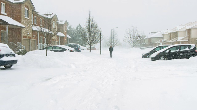 一名男子在郊区的暴风雪中行走。视频素材