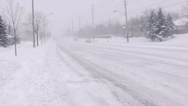 汽车在暴风雪中行驶在下雪的街道上。视频素材