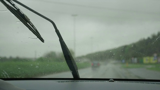 特写:在高速公路上擦拭汽车挡风玻璃上的雨滴视频素材