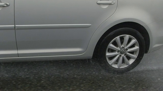 慢镜头特写:汽车在雨中行驶在潮湿的道路上视频素材