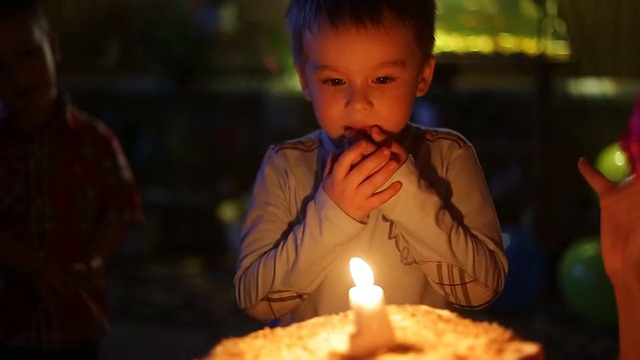 特写小男孩吹灭蛋糕上的蜡烛视频素材