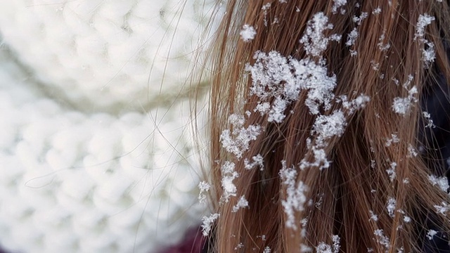 年轻女子戴着白色的帽子和围巾，头发上戴着雪视频素材