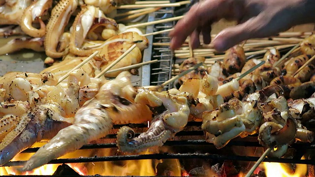 小贩在泰国传统街头食品市场烤鱿鱼视频素材