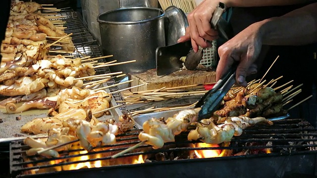 小贩在泰国传统街头食品市场烤鱿鱼视频素材