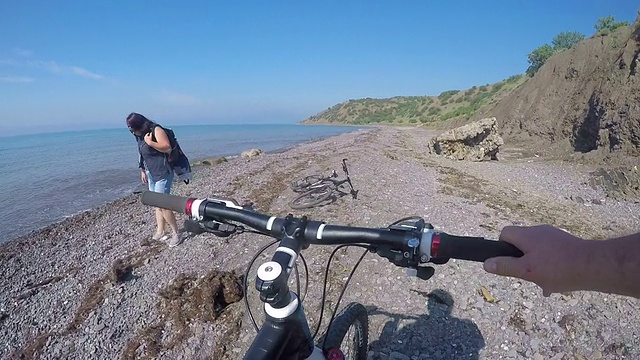 骑自行车的人的观点旅行者推着自行车沿着野生卵石海滩视频素材