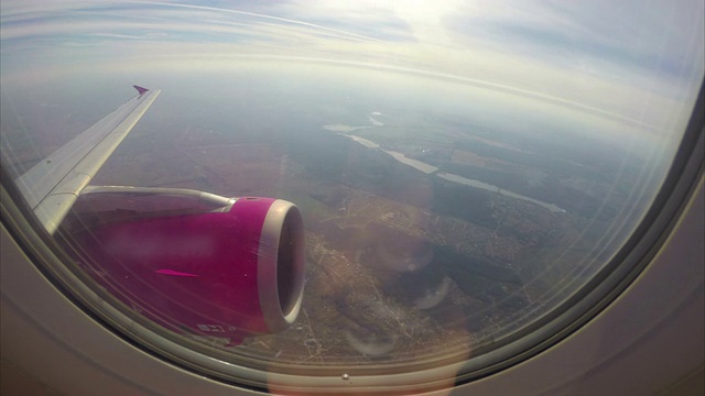 在城市上空飞行的飞机，飞机舷窗乘客pov。飞机高空载客，客机机翼涡轮和舷窗云雾，飞机内景拍摄，国际喷气飞行运输，白天的天空视频素材