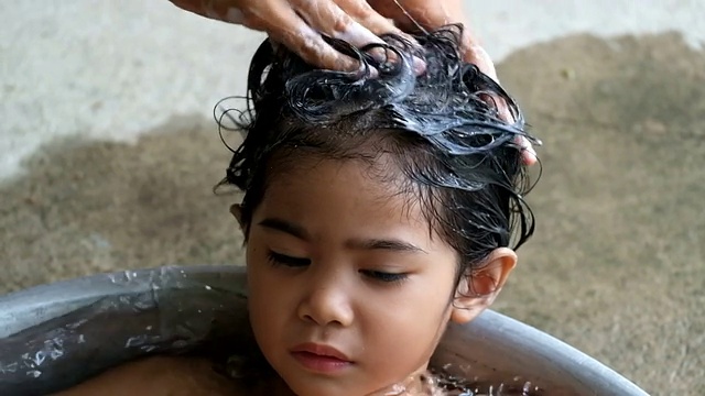妈妈双手用香波给女儿洗头发，妈妈正在洗山羊皮视频素材