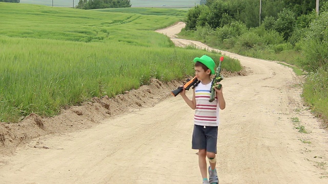 男孩拿着玩具枪在路上，一直在服役，守卫着视频素材