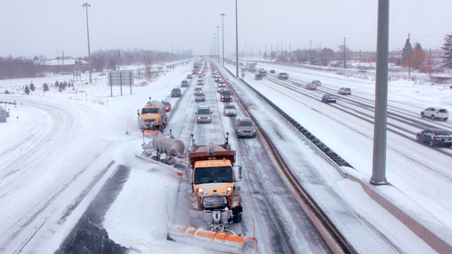 在一场暴风雪中，在繁忙的高速公路上有多台巨型扫雪机。视频素材