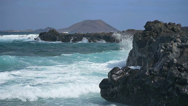 慢镜头:海浪拍打着海面上的岩石峭壁视频素材