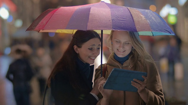 女性朋友在城市的雨天晚上使用触控板视频素材