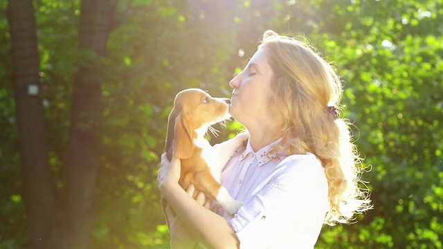 美丽的女人和她的小猎犬在公园里玩。慢动作视频素材