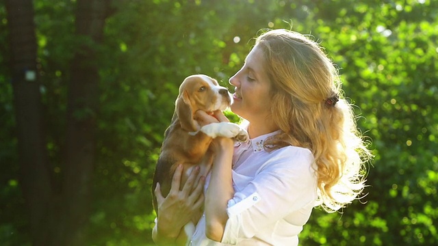 美丽的女人和她的小猎犬在公园里玩。慢动作视频素材