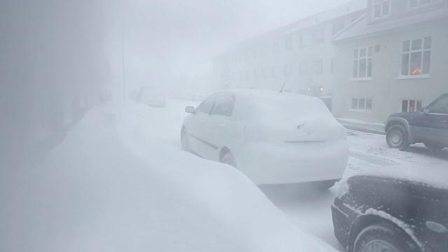 冰岛雷克雅未克，白雪覆盖的雪堆阻塞了居民区的人行道上的汽车视频素材