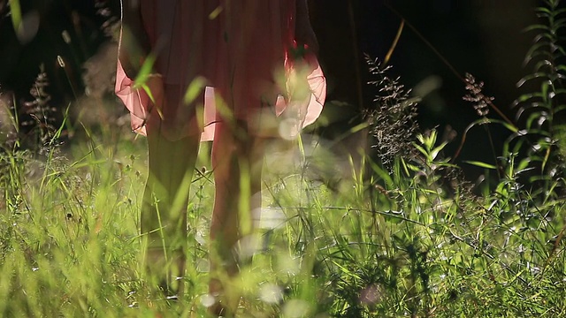 穿着淡雅夏装的女孩在阳光明媚的户外走在田野里视频素材