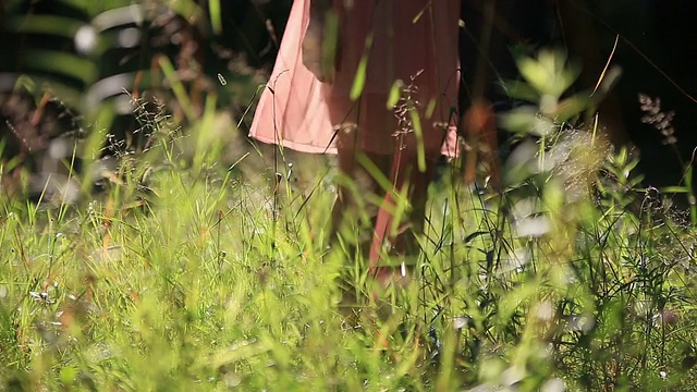 穿着淡雅夏装的女孩在阳光明媚的户外走在田野里视频素材