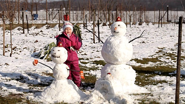 快乐的小女孩堆了两个雪人视频素材