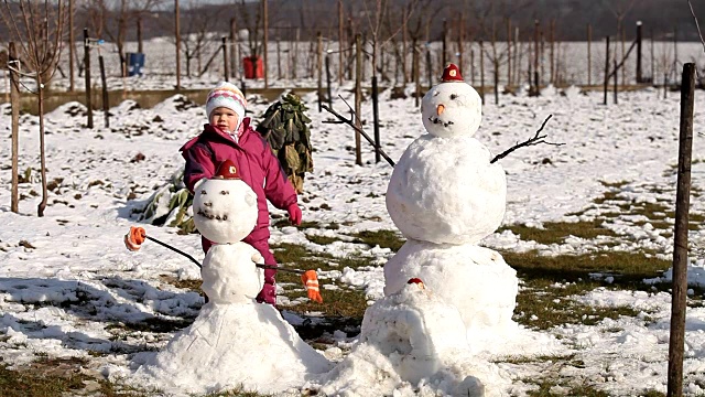 快乐的小女孩堆了两个雪人视频素材