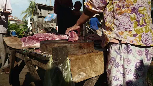 小贩用斧头在砧板上切肉视频素材