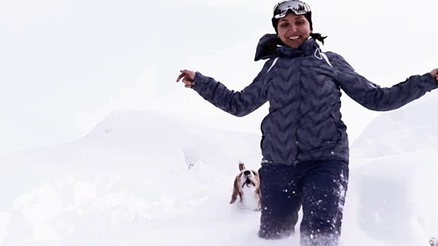 小猎犬和他的主人在雪地里奔跑，享受他们的寒假视频素材