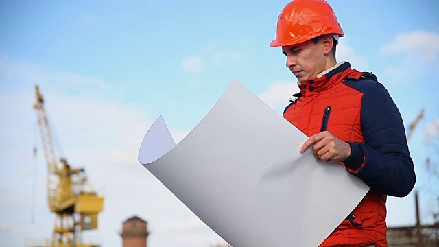 男人建筑师肖像建设者在橙色头盔看起来仪器项目对蓝色的天空和建筑视频素材