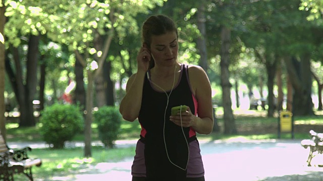 年轻女子在手机上选择音乐视频素材