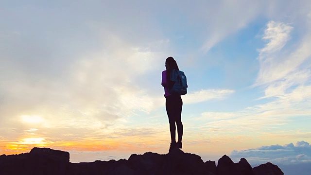 日落时分，一位孤独的女性在庆祝她的登山成功视频素材