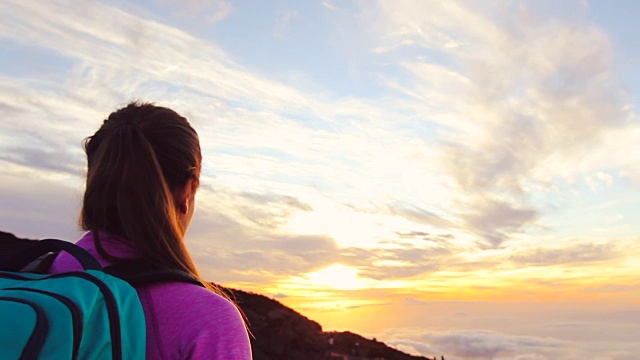 徒步旅行。背着背包走向夕阳的女徒步旅行者。徒步女孩独自行走在美丽的自然风景中。视频素材