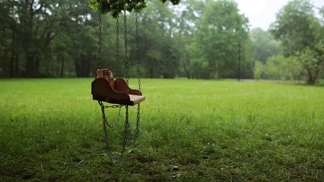 空空的木秋千在雨中慢慢地摇摆视频素材